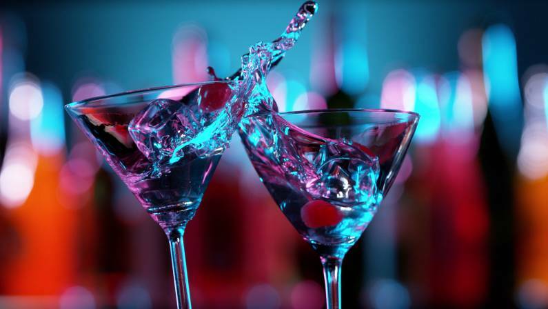 Closeup of splashing martini cocktails in cheers gesture.