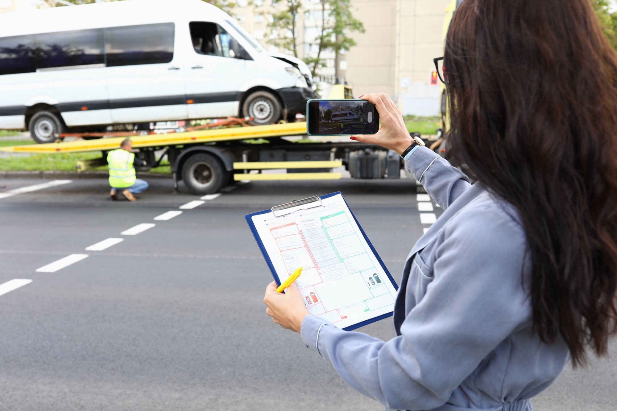 Woman with documents hands taking pictures wrecked car phone